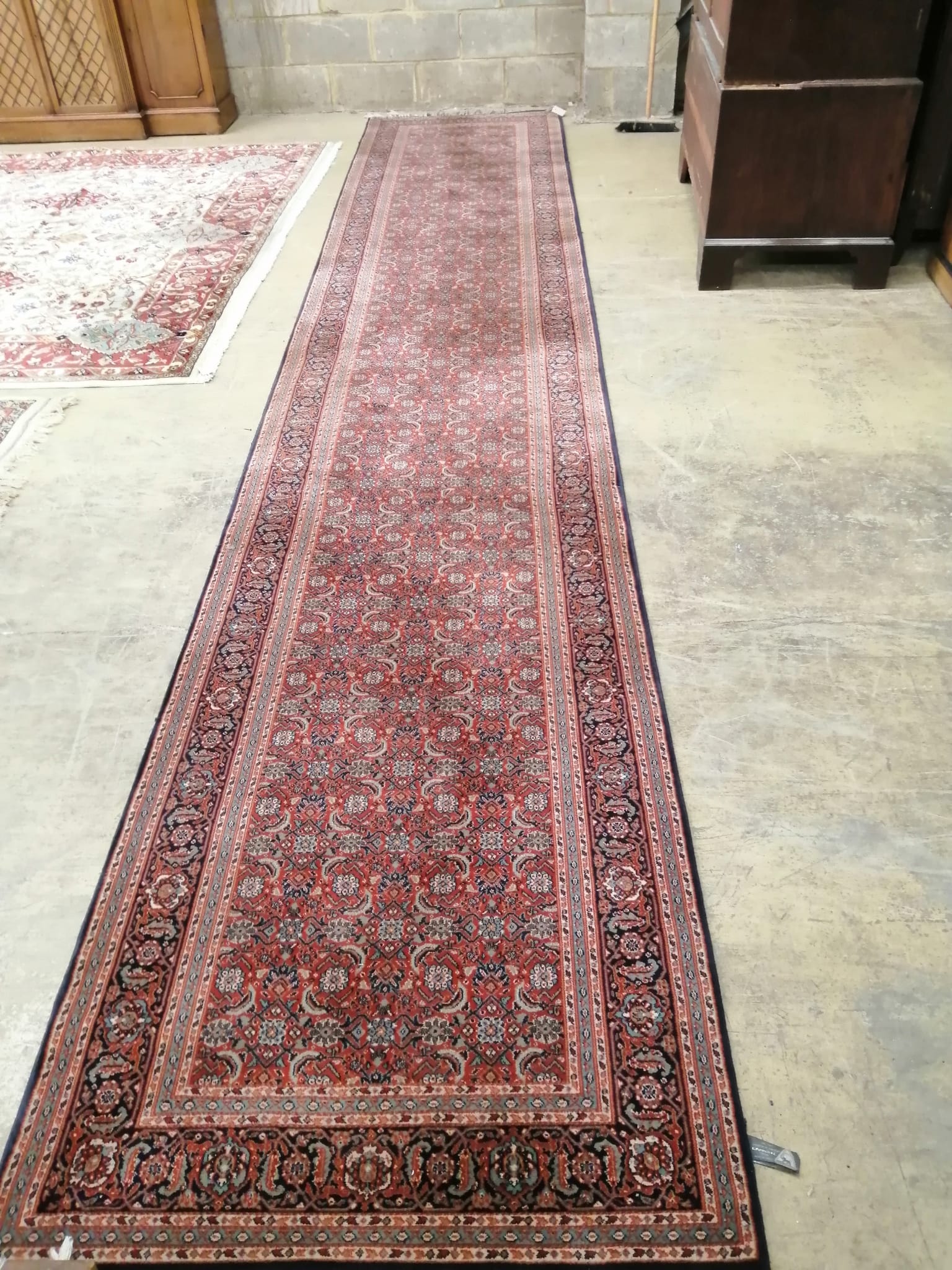 A machine made Belgian, North West Persian style, red ground runner approximately 540cm x 100cm